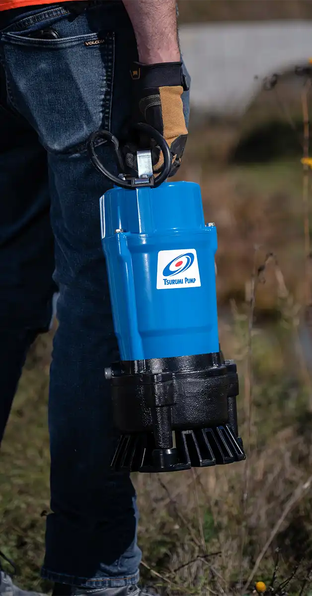 Un travailleur transporte une pompe Tsurumi de série HS